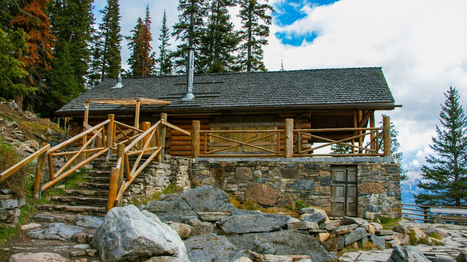 Furnished cabin-style vacation rental with a wooden porch and outdoor seating surrounded by pine trees